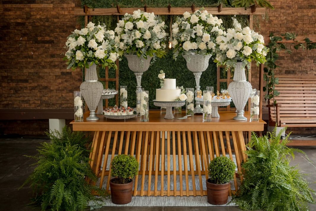 Mesa de bolo de casamento com arranjos de rosas brancas